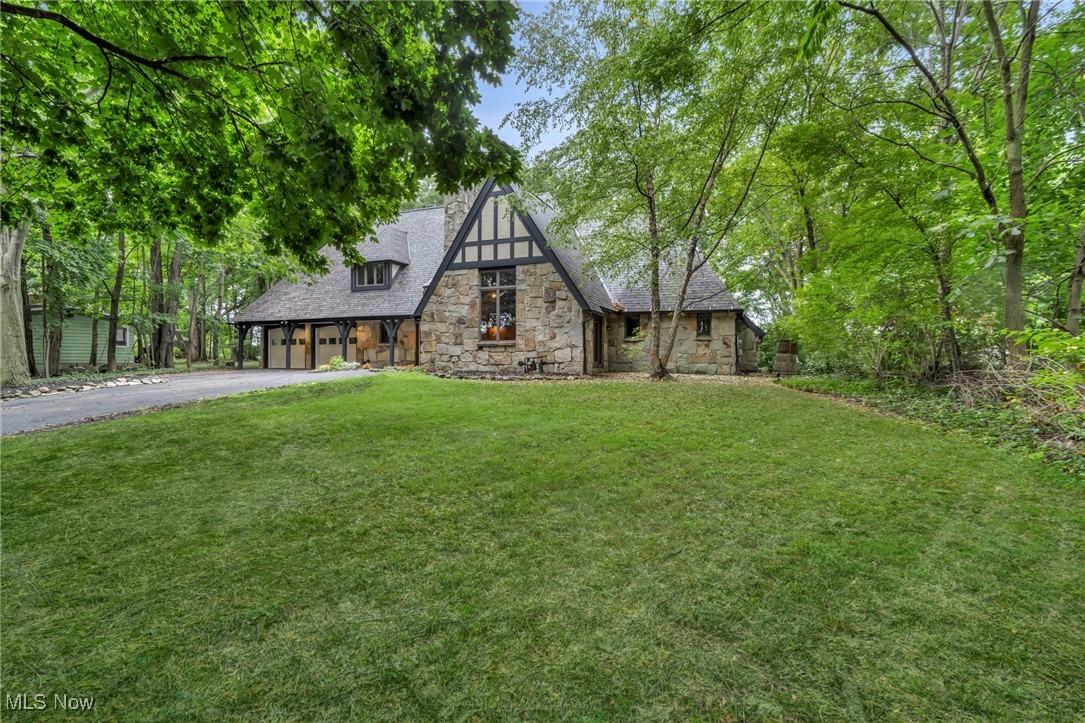 Perched above the Chagrin River, this French Tudor estate is less a house and more a retreat—timeless, elegant, and just minutes from the heartbeat of Downtown Willoughby. Step inside and you’re greeted by soaring ceilings, a grand stone fireplace, and sunlight streaming through walls of windows—an elegant backdrop for both quiet mornings and lively gatherings. The kitchen invites connection, perfect for cooking, cocktails, or conversations that last late into the night. Retreat to the first-floor primary suite, where wooded views and a spa-inspired bath create a private sanctuary. Upstairs, spacious bedrooms provide comfort for guests, while every corner of the home tells a story of warmth, character, and craftsmanship. Outdoors, the stone patio and acre of land overlooking the river offer endless opportunities for dining al fresco, summer celebrations, or quiet reflection. From cozy nights by the fire to weekends exploring nearby shops and restaurants, life here feels both grand and grounded and holds rare potential as a destination Airbnb. Minutes from Lake Erie’s beautiful beaches, sunsets and Downtown Cleveland. Low utility costs and taxes make this the perfect investment. More than a home—it’s a lifestyle of privacy and comfort. Member of owner LLC is a licensed real estate agent.