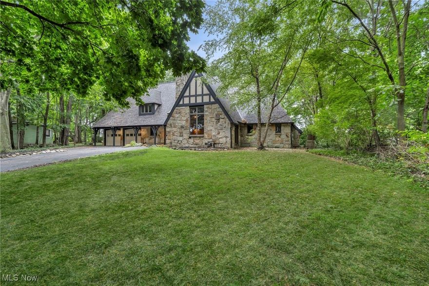 Perched above the Chagrin River, this French Tudor estate is less a house and more a retreat—timeless, elegant, and just minutes from the heartbeat of Downtown Willoughby.  Step inside and you’re greeted by soaring ceilings, a grand stone fireplace, and sunlight streaming through walls of windows—an elegant backdrop for both quiet mornings and lively gatherings. The kitchen invites connection, perfect for cooking, cocktails, or conversations that last late into the night. Retreat to the first-floor primary suite, where wooded views and a spa-inspired bath create a private sanctuary. Upstairs, spacious bedrooms provide comfort for guests, while every corner of the home tells a story of warmth, character, and craftsmanship. Outdoors, the stone patio and acre of land overlooking the river offer endless opportunities for dining al fresco, summer celebrations, or quiet reflection. From cozy nights by the fire to weekends exploring nearby shops and restaurants, life here feels both grand and grounded and  holds rare potential as a destination Airbnb. Minutes from Lake Erie’s beautiful beaches, sunsets and Downtown Cleveland. Low utility costs and taxes make this the perfect investment. More than a home—it’s a lifestyle of privacy and comfort. Member of owner LLC is a licensed real estate agent.