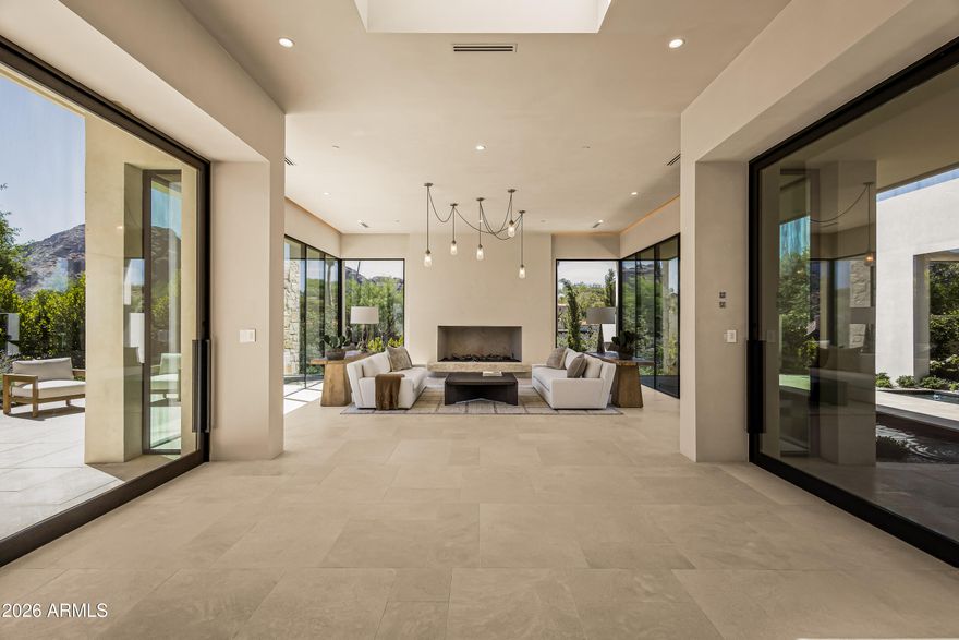 Set behind gates on a pristine acre lot in Paradise Valley, this extraordinary custom estate showcases timeless architecture, exceptional craftsmanship, and breathtaking mountain views. Constructed with all-steel framing and thoughtfully curated at every turn, the 5,780 sqft home offers 4 beds, 4.5 baths, a private office, gym, and detached guest house. A study in refined European minimalism, the open concept floor plan features soaring 12' ceilings, Venetian plaster walls, designer lighting, and dramatic walls of glass framing Camelback Mountain, Mummy Mountain, and the Phoenix Mountain Preserve. Exquisite finishes include Calacatta Viola marble, limestone, custom molding, floating vanities, and premium fixtures throughout. The chef's kitchen flows seamlessly into the dining and living spaces, anchored by a gas fireplace and sophisticated wet bar designed for effortless entertaining. The primary retreat delivers a true spa-like experience with dual vanities, enclosed water closets, an expansive walk-in shower, soaking tub, and a showroom-style custom dressing room complete with makeup station, laundry, and garment steamer. A connected private gym further enhances the suite's resort-inspired feel. The detached guest house features a full bedroom and bath, living area, and wet bar--ideal for extended stays, multigenerational living, or elevated guest accommodations. Outdoor living rivals Arizona's finest resorts with a pool and water feature, oversized spa, outdoor kitchen, ramada, covered patio with gas fireplace, expansive lawn, and professionally curated grounds designed by Berghoff Design Group. Additional highlights include a 4-car garage and commercial-grade home automation system with integrated surround sound and security. Located within the coveted Hopi School District and moments from premier golf, luxury resorts, fine dining, and upscale shopping, this residence embodies the very best of Paradise Valley living.