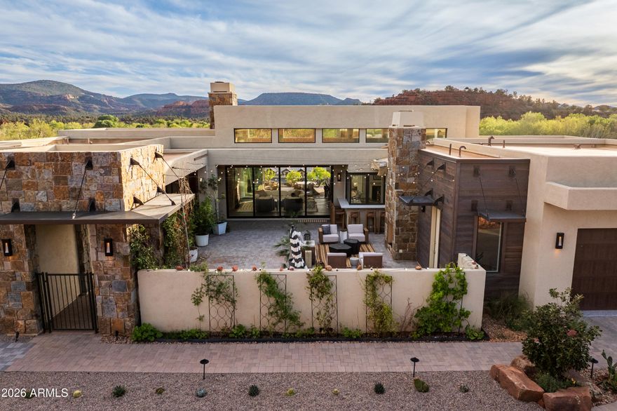 Set across a rare double lot, unfolding between rock and sky, where architecture settles naturally into Sedona's landscape. Outdoor living is anchored by a sculpted pool and spa, with layered spaces for gathering or quiet retreat, organized around a shaded pavilion, framed by open land and red rock views. The transition indoors is seamless, with expansive openings that draw the landscape in. In the main living space, volume and light define the experience, with 16-foot ceilings and clerestory windows introducing a soft, ambient glow. Clean lines, grounded materials, and a striking stone fireplace create a setting both expansive and composed. Above, a rooftop terrace offers an elevated vantage point for sunset, stargazing, and uninterrupted views of Sedona's surrounding beauty. Broker Owner Beyond the primary living spaces, the scale of the double lot allows the property to function with a level of flexibility rarely found in Sedona. Outdoor areas unfold as a series of distinct zones, each with its own orientation and purpose. The pavilion anchors one of these spaces, while others remain open to the landscape, preserving long sightlines and a strong connection to the natural terrain. Just beyond the pool area, a private trail extends nearly 100 yards into the junipers, following natural animal paths and offering a quiet, immersive connection to the land.

The home's layout is both intuitive and adaptable. It includes three full-size bedrooms, complemented by a generous office that can easily serve as an additional sleeping area when needed. The owner's entry has been fully upgraded to function as a practical transition space, ideal for storing hiking gear, outdoor equipment, and kitchen overflow. A large laundry room adds further flexibility, with enough space to accommodate projects, storage, or utility use beyond its primary function.

Interior circulation maintains clear sightlines while allowing for separation where needed. Clerestory windows bring in consistent natural light while preserving privacy and uninterrupted wall space. Material selections emphasize durability and restraint, with finishes chosen to age well and remain visually quiet over time. The stone fireplace anchors the main living space, balancing the openness created by the volume above.

The landscaping extends the livability of the property, blending cultivated and native elements. Multiple fruit trees--including nectarine, peach, apple, and plum--are complemented by a row of berry bushes and a curated collection of flowering cacti integrated into the natural desert palette.

Located within Sedona Ranch at Oak Creek, the property also benefits from a rare connectivity advantage: direct access to the Village of Oak Creek via Verde Valley School Road and to West Sedona via Red Rock Loop Road. This dual access is both highly practical and unique to this exclusive community, offering flexibility in daily movement while maintaining the sense of separation and quiet that defines the setting.