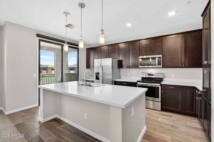 Immaculate move-in ready end-unit condo with 2 beds, 2 baths, and all living space on one level on the desirable second floor with no neighbors above plus an attached two car garage. Luxury gated community with heated pool, BBQ area, ramada, fireplace, greenbelts, walking paths, and dog park. HOA covers roof, exterior maintenance, landscaping, and common areas. Split floor plan offers privacy and abundant natural light. Private covered patio overlooks a large grassy area with open views. Kitchen features quartz counters, island, upgraded cabinetry, stainless steel appliances, and open flow to the great room and dining area. Spacious primary suite includes a walk-in closet. Upgraded fixtures throughout. Large laundry room with storage. Ideal lock & leave or seasonal home.