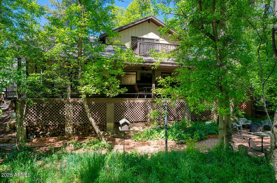 Two-story log-sided cabin in Christopher Creek just outside Payson, Arizona. 2 bedrooms, 2 bathrooms, loft, office, 1,869 sq ft on a wooded lot with no HOA. Most people don't believe a place like this exists in Arizona. Towering pines, mature oaks, AZ Black Maple trees, crabapple trees, grape vines, lavenders, ferns, wildflowers, and a seasonal creek bed, all on one property. An entire ecosystem you never knew Arizona had. As soon as you pull up, winding brick pathways guide you through the yard past a decorative wooden footbridge, a porch swing under the trees, a fire pit patio, and a picnic area all shaded by a canopy so dense every season brings a completely different feel to this property. A ''Welcome'' sign greets you at the covered front porch and deck where you can sit with your morning coffee and watch the elk, deer, squirrels, blue jays, turkeys, and other wildlife. Step inside and see the beautiful hardwood baseboards and trim, and the brand-new 22m Luxury Plank vinyl flooring runs throughout the main level. The living room is the heart of this home with vaulted ceilings, skylights pouring in natural light, and a wood-burning fireplace installed in 2024 that will keep you warm on those cold mountain nights. The kitchen connects right to the living and dining area with newly updated appliances that include an electric stove, built-in microwave, dishwasher, disposal, refrigerator, walk-in pantry, and additional storage under the stairs. Everything you need and nothing you don't. Head upstairs to the master suite with a full bathroom and step out onto the balcony for tree-top views you won't find anywhere else. Yes, this home has 2 separate decks! The loft overlooks the living room below and works perfectly as a reading nook, guest space, or second office. The separate den/office is also upstairs, giving you a quiet, dedicated workspace away from the main living areas. Tons of storage throughout the home, you won't be left looking for space. Back on the main level, the second bedroom has easy access to the second full bathroom. Now let's talk about the outside, because this property is something special. Brick pathways connect the covered patio, multiple seating areas, a storage shed, a bridge, and a workshop. The detached carport keeps your vehicle covered, there's RV hookup & RV parking for your toys, and enough space to park 8 vehicles. Chain link fencing secures a majority of the perimeter. No HOA fees. Christopher Creek sits just off Highway 260 in Gila County, less than 25 minutes from downtown Payson where you'll find shopping, dining, and everything you need. Whether you're looking for a mountain second home, a vacation rental property, or a permanent residence, this home in the pines is the one you've been searching for!