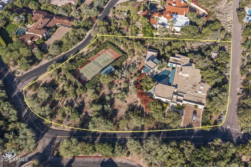 Set on 1.61 acres at the base of Mummy Mountain, this Paradise Valley property offers a rare combination of privacy, scale, and iconic surroundings. City lights shimmer in the distance while Camelback Mountain commands striking views to the south. An existing home with a dramatic view deck and private tennis court sits on the lot, offering immediate character and long-term vision. Whether thoughtfully reimagined or replaced with a custom build-to-suit estate, the setting supports something truly special. Tucked within a quiet, secluded neighborhood just moments from Paradise Valley Country Club, this is an exceptional canvas for a truly bespoke retreat.