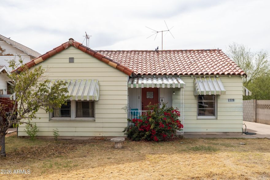 Rarely does an opportunity arise that combines historic charm, long-term investment value, and one of Phoenix's most coveted addresses. Welcome to 2220 N. Edgemere Street, a distinguished 1931 brick residence in the heart of the Coronado Historic District, where historic tax incentives, architectural integrity, and an unbeatable location converge to make this one of the most compelling investments on the market today. Situated on a nearly 6,000 square foot lot on one of Coronado's most desirable blocks, this home enjoys a quiet, low-traffic street that connects minimally to surrounding thoroughfares, creating a peaceful and exceptionally safe environment. A charming front conversation stoop welcomes you home and sets the tone for the warmth within. Walk out the front door and you are steps from beloved local coffee shops, acclaimed restaurants, and the iconic Sunshine Market, placing you in the heart of one of Phoenix's most walkable urban neighborhoods. The home's red brick construction remains protected beneath aluminum siding installed in the 1960s, accompanied by functional period awnings over the windows that keep the home naturally shaded and cool. For the visionary investor, that siding represents genuine upside, as the original brick underneath is very likely in excellent condition and ready to be revealed. The classic clay tile roof crowns the property with timeless character and lasting durability. Step inside and the elegance of a bygone era unfolds immediately. Soaring coved ceilings, original plaster walls, and original oak hardwood floors create an atmosphere of warmth and craftsmanship rarely found today. The living room is anchored by a stunning picture window that floods the space with natural light and a wood-burning fireplace that adds undeniable charm. A beautifully shaped historic arch frames the passage from the living room into the formal dining room, an architectural detail that is distinctly of its period and simply irreplaceable. Historic built-ins in the dining room and hallway, original paneled hardwood doors with period hardware, and a delightful in-wall kitchen ironing board round out a home that has held onto its soul. Infrastructure updates completed in the 1980s, including work on the kitchen, bathrooms, and a partial ABS sewer line update, have laid the groundwork so that this house is truly ready for its next chapter. The HVAC has been well maintained and recently serviced with a technician-assessed remaining life of at least two to five years, and the water heater is newer. The large detached garage presents a ready-made opportunity to construct an Accessory Dwelling Unit, which would command strong rental income in one of Phoenix's most in-demand neighborhoods and significantly enhance the property's income-generating potential. Combined with Coronado's historic tax benefits, 2220 N Edgemere is not just a beautiful home. It is a rare and intelligent investment in one of Phoenix's most vibrant communities!
