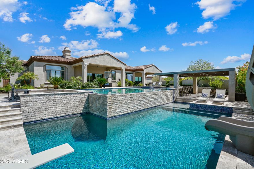 Welcome home to this North Scottsdale beauty with a resort-like back yard! Enter
through the welcoming courtyard complete with palm trees, outdoor fire pit and
water feature. Step through the front door and into a large great room with beautiful
stacked stone fireplace. The attached gourmet kitchen has a huge island, massive
Sub-zero refrigerators, double ovens, Wolf cooktop and built-in pebble ice maker!
Desirable split floor plan has 4 bedrooms and 3 ½ baths in main home and 1
bedroom and full bathroom in attached casita with it's own entrance. Open floor plan includes 2 3-panel sliding glass doors that open completely to bring the outside in and make entertaining a breeze. Step out back to an entertainer's paradise! One of a kind multi-tiered pool with swim-up bar, diving board, slide, and basketball hoop. But that's not all! Gather around the fire pit, practice your putt on the putting green or do some tricks on the in-ground trampoline while your meal is being prepared in the outdoor kitchen complete with built-in BBQ, sink, and hibachi grill.

Bring all your toys! Home has an attached 4-car garage and a hard to find detached 30' x 30' RV garage.

Work from home? No problem. Primary suite includes a home office with two built in desks and cabinetry. Give your kids and guests some extra space with the bonus area between the spare bedrooms. Additional features include a laundry room with 2 washers and 2 dryers {Included}, circular driveway, and large grassy areas in the backyard. Don't miss out on this opportunity!