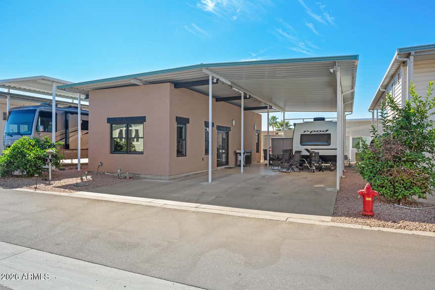 MOVE IN READY! This is a spacious RV lot with a 3-year-new stick built AZ home. This home has a plethora of upgrades to include Anderson mirrored-tinted windows, R19 walls, R38 ceilings, 9' ceilings, granite counter tops, mini-split HVAC,  ''Zip'' sheathing system, & a fresh air exchanger. Kitchen includes Frigidaire appliances. The covered RV port is 12 feet in height with plenty of room for an outdoor patio. GOLF CART (with 1 yo lithium batteries) & OUTDOOR BBQ ARE INCLUDED! Happy Trails RV Resort is a 55+ active adult, guarded community featuring an on-site restaurant, post office, low HOA dues, & NO LAND LEASE! Experience AZ living and a vibrant social scene. This is more than a home - it's a lifestyle! Conveniently located in Surprise, AZ near shopping, medical, golf, sports, & more.