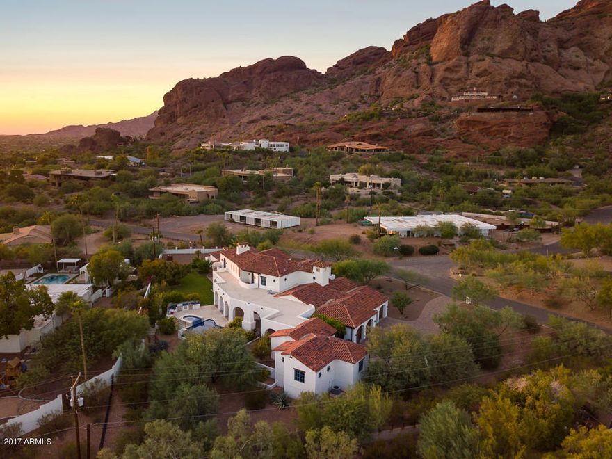 LUXURY / WARMTH / FUNCTION are the hallmarks of this Beautiful Spanish Colonial HOME; built from the ground up in 2010. With a regal presence situated on the south side of Camelback Mtn, this ONE OF A KIND home combines an elevated caliber of construction & pristine architecture with magnificent downtown Phoenix & Camelback Mountain views. The 7,077 SF Main house offers 4 EnSuite Bedrooms with a downstairs Master Retreat & 6.5 baths, a bright airy living room open to the elegant rustic kitchen, an exquisite dining room, a casual media /game room w/ hand finished built ins, an office, library and meditation room. 
Everywhere you look, you know this is a special property - from the hand distressed hardwood hickory floors to the custom chandeliers and artisan tile, beautifully curated from.. ...every corner of the world specifically for this home.
The 1,105 SF fully self-contained guest house has two bedroom and one oversized custom finished bath, a separate entrance and a full kitchen and laundry. This would be a perfect MIL, au pair, or guest residence.
Love the interior but then step outside and be astonished by the exterior with 360 degree views of Camelback Mountain, Papago Buttes, and the Downtown Phoenix skyline. Full length covered terraces invite you to enjoy the fireplace, out door kitchen featuring a green egg, cerulean blue tiled infinity pool and raised spa, and plenty of lush green grass and landscape. Truly a one of a kind!



ADDITIONAL INFORMATION:
 -    Designed by Robert Brown of Montgomery Design Group
-	The home sits on .97 of an acre
-	Circular drive in front
-	Front courtyard entry with a fountain and an Isokern fireplace
-	Four car side entry garage has 9' entries, additional storage and epoxy flooring
-	Construction is 2x6 throughout & 2 x 12 and 2 x 24 along some exterior walls to allow the deep set window wells typical of this stye architecture.
-	Architectural features include: mud set tile roof, iron gratings, window lintels where appropriate, a bell tower with weathervane (also acts as a lightening rod), copper flashing and scuppers.
-	Doors and windows are by Sierra Pacific
-	Front entry door is arched alder with multiple panes of translucent glass
-	Interior floors are solid hickory hardwood
-	Family room fireplace is by Isokern with a canterra stone surround
-	Staircase has custom wrought iron railings and hickory treads, upstairs railing heights are higher than code for added safety
-	Staircase tile risers are from Ann Sacks â“ Antique Parefeuille Terracotta
-	Ceiling feature center cut solid wood beams
-	Wine Room with a 540 +/- capacity and dual zone temperature control
KITCHEN
-	Wolf 48", 6 burner stove w/ griddle and 2 ovens
-	Wolf wall oven
-	Wolf microwave
-	Two Asko dishwashers
-	Side-by-side SubZero fridge and freezer drawers
-	SubZero ice maker
-	Perimeter cabinets are off white stained alder with black honed granite counters
-	Custom furniture island is knotty alder with hand painted red Mexican tiles
-	Talavera tile backsplash
-	Pot filler
-	Oversized wrought iron island chandelier
-	Large walk-in pantry and butlers pantry
-	Kitchen flooring is reclaimed French roof tiles
DINING ROOM
-	Double French doors open to the front courtyard
-	Pitched ceiling with center cut solid wood beams
-	Large chandelier from Italy
MEDIA ROOM
-	Built in entertainment center accommodates a 64" TV
-	Wet bar with a pewter sink
-	SubZero mini fridge
-	Alder cabinets with a special locking liquor cabinet
-	Flooring is De Golpe Manganese Saltillo
-	Whimsical hand painted Mexican tile adorns the wet bar
-	Full bath off the media room  has direct pool access.
MASTER SUITE
-	Groin vaulted ceiling treatment in the vestibule
-	Isokern fireplace
-	Center cut solid wood beam ceiling
-	French doors to the covered terrace
-	Wterworks Carrera marble tile with limestone insets in the luxurious His / Her bath
-	Calista free standing tub
-	Concealed safe
-	His and Her closets with extensive solid wood built-ins
LIBRARY
-	Fully paneled in alder wood
-	Coffered ceiling
-	Library ladder
-	Built in file drawers and printer cabinets
-	Private balcony with downtown Phoenix views
EXTERIOR
-	Negative edge pool with hand painted porcelain tile.
-	Heated pool and spa
-	Salt water pool
-	Pool decking is Marbella stone
-	Ourdoor kitchen with a Big Green Egg
-	Four burner Lynx grill
-	Lynx fridge
MECHANICAL
-	The main house has underground returns and a total of 17 tons of AC, all 14 SEER: 2 5 ton Lennox units with gas furnaces, 1 2 ton Lennox unit with a gas furnace, 1 5 ton heat pump.
-	Guest house is services by a 3 ton Lennox heat pump
-	6 amp service
-	Cat 5 wiring throughout with multiple places to add media
-	Power lines have been buried on the property
-	75 gallon hot water heater and 3 tankless hot water heaters
-	Toto toilets throughout
-	Extra insulation throughout
-	Extra wide joists and subflooring and insulation on second floor for sound control