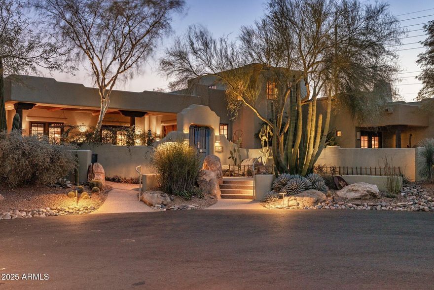 A Rare Private Retreat Set against the desert and bordering a mountain preserve, this estate invites a sense of calm that lingers. Inside the gated grounds, a hidden sanctuary unfolds lush, private, and entirely unexpected. Positioned on two expansive corner parcels, the 6,868 SF residence is enclosed by an elegant perimeter walled fence with a gated entry enclosing a private circular drive, offering true seclusion and a refined sense of arrival. The estate is meticulously curated with rich native vegetation, featuring towering cacti, sculptural agaves, and jewel-toned succulents that transform the desert into a refined, resort-style landscape. A tranquil water feature with a solid stone bridge serves as a striking architectural focal point, while professionally designed landscape lighting by a world-renowned lighting designer adds depth, drama, and enhanced privacy after dark. Ideal for both grand entertaining and quiet retreat, the residence offers 6 bedrooms and 7 bathrooms, including three private primary suites, seven patios, and a well-appointed detached guest casita for extended guest stays or multigenerational living with privacy in mind. An indoor pool and spa within a 2,500 sq ft pool house provides year-round enjoyment. The home is single-level, complemented by a sky deck offering elevated views of the McDowell Mountains, accessed by private elevator or stairways for easy enjoyment by all. Four fireplaces located in the living room & three primary suites with one outdoor fireplace and a fire pit add warmth and architectural distinction throughout. Custom details define the residence, including refined solid-wood Dutch doors and a thoughtfully integrated indoor dog wash station, reflecting a seamless balance of elevated design and everyday convenience. Bordering the McDowell Mountain Preserve, the property enjoys permanent, unobstructed views and a rare sense of protected openness. The coveted north/south exposure delivers exceptional natural light throughout the day, allowing for both sunrise and sunset viewing while enhancing comfort and livability. Homes of this scale, privacy, and setting are increasingly uncommon. This is not simply a residence, it is a distinctive desert sanctuary, offering timeless appeal in one of the region's most protected and sought-after environments.