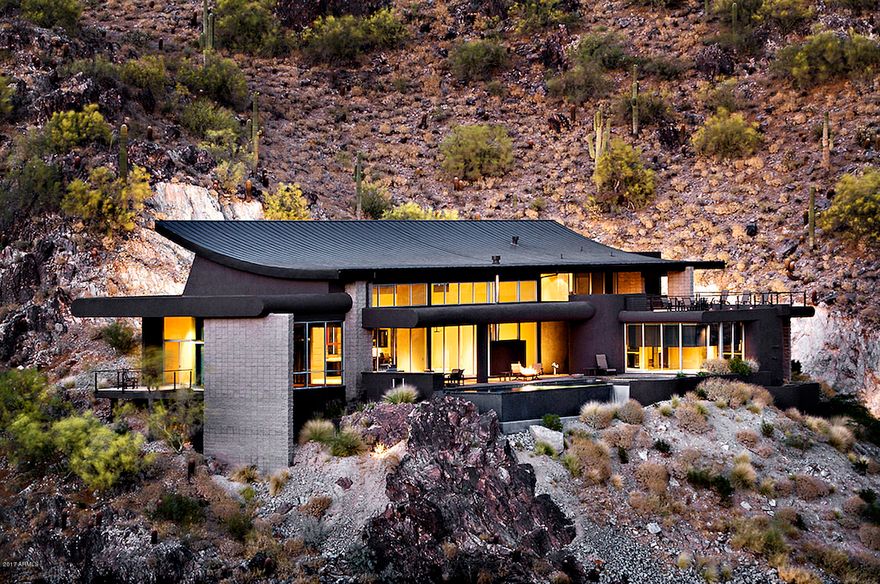 $395,000 PRICE REDUCTION! Breathtaking panoramic city-light and Mountain Preserve views! This extraordinary one-of-a-kind contemporary design by CP Drewett features a great room and open kitchen with soaring 30' ceilings, 24'' limestone flooring, and walls of glass opening to the extensive patio, pool and spa areas with spectacular Valley views. The chef's kitchen features high-end appliances and views. Master suite offers a sitting/TV room with an open gas fireplace shared with the bedroom, a luxurious bath with steam shower, and a second view deck. The home also offers a fully-equipped media room, Crestron home automation, electric shades throughout, and separate guest house with its own living room or 4th bedroom. Ultra-efficient solar panels blend seamlessly with the metal roof providing little to no monthly power expense.