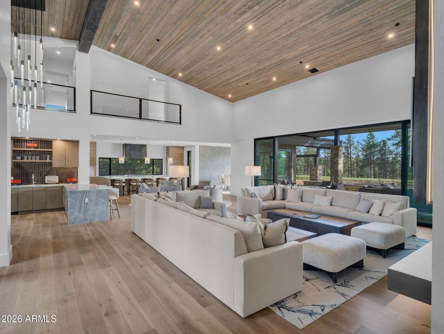 Completed in 2025, this exceptional custom modern mountain estate is set along the 4th fairway of Pine Canyon's award-winning golf course, blending striking architecture, refined craftsmanship, and sweeping fairway views into one unforgettable residence.
Thoughtfully designed across 5,833 square feet, this 4-bedroom, 4 full bath, 2 half bath home rests on a ½-acre homesite framed by towering pines--offering a rare balance of privacy with premier golf course frontage. From arrival, the home makes a bold architectural statement. Clean contemporary rooflines are complemented by natural stone accents, warm wood siding, and a sweeping paver driveway, setting the tone for the sophisticated modern mountain aesthetic within. Inside, soaring ceilings and expansive walls of glass flood the interiors with natural light while perfectly framing the surrounding landscape. A striking floating modern staircase serves as a sculptural centerpiece, reinforcing the home's architectural intent. Custom wall coverings are featured throughout, adding depth, texture, and a cohesive layer of curated sophistication.
The great room is a true showpiece anchored by a custom metal linear fireplace set atop a floating concrete hearth with a custom plaster finish. A large bar and lounge area enhances the space, creating an ideal setting for entertaining, relaxing, or gathering after a day on the course. Bespoke designer lighting and seamless indoor-outdoor flow elevate the experience for both elegant hosting and relaxed mountain living.
The kitchen is both dramatic and highly functional, centered around a massive waterfall-edge island with seating and sleek custom cabinetry. A uniquely paneled Sub-Zero refrigerator integrates seamlessly into the design, while statement custom lighting and a picture window draw forest and fairway views directly into the heart of the home. A large butler's pantry and secondary "hidden kitchen" provide exceptional prep and storage space, complete with a second refrigerator and double ovens perfect for entertaining at scale.
The primary suite is a private retreat, featuring a spa-inspired bath and an expansive custom closet outfitted with an infrared sauna and dedicated laundry, offering a resort-level daily living experience.
Upstairs, a generous game room with vaulted, beam-accented ceilings creates a versatile gathering space. This level features a built-in bar with refrigeration, a coffee bar, pool table, and access to a large balcony ideal for hosting, relaxing, or enjoying elevated views of the surrounding pines and fairway.

The well-planned floorplan offers private bedroom retreats, multiple gathering spaces, and thoughtful separation for comfort and flexibility. Throughout the residence, meticulous craftsmanship, elevated finishes, and contemporary design elements define every space.
Whether hosting après-golf evenings, enjoying quiet mornings overlooking the fairway, or gathering with friends and family on weekends, this residence delivers the signature Pine Canyon lifestyle luxury, nature, and timeless design.
A rare opportunity to own a nearly new, custom masterpiece with premier golf course frontage in one of Northern Arizona's most prestigious private communities.