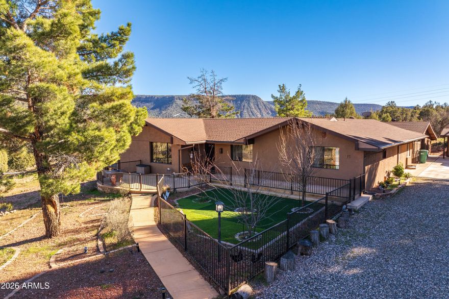 Well done equestrian estate in Sedona, which comes with rare 3.42 acres and borders natural forest land, located on the South side of Oak Creek Village. Plenty of space for multi-family living within these well-appointed walls providing 3592 square ft of living space. A detached  in-law/caretaker quarters with its own private heating and air conditioning, fire-sprinklers and safety features is keypad accessible with a shared fenced yard for pets. This property is within minutes of grocery store, restaurants, Sedona Spa with pickleball, tennis, and pools. and shopping yet away from the heavy traffic. The property includes a large double garage with separate workshop and a single garage and plenty of parking for large and small vehicles. The main house had extensive up-dates and a 2021 re-model with new knotty pine kitchen cabinets and ceiling, all new appliances, wood floor, new bathroom vanities and faucets, paint etc. The main house has two bedrooms, 2-bathrooms with walk-in closets and a sunny laundry room. The large spacious family room has gorgeous cedar wood ceiling beams with wood burning fireplace, dining area, and counter bar. The large open floor plan was thoughtfully designed to allow its owner to easily open the many windows for fresh cross breeze ventilation. Also, out the windows you will find your gaze drawn outward to beautiful views of the surrounding Sedona mountains in all directions. The slider door opens up to a covered new Trex deck and enclosed courtyard which leads to another bedroom and sitting room or office and a separate in-law quarters.
The entire outside yard area and entrance to the property around the house is all graveled and enclosed with custom rod iron fencing large gates and a new brick circular walled patio overlooking a large area of level grounds which could accommodate at least up to six horses and room for a barn and large paddock for boarding. There is ample room for full turn around with tow trailer in driveway. The front of the house has an enclosed patio with rod iron fencing with beautiful landscaping, synthetic turf, and walkways. The rest of the entire property is covered with pinion and ponderosa pines. A seasonal creek runs nearby, and the national forest is your neighbor. This property is in a quiet and private cul-de-sac away from the hustle bustle but within minutes of the local grocery store, restaurants, and Sedona Spa with pickleball, tennis, and pools. Property is easy to show with two hour advance notice. This property allows two animals per acre per Yavapai County code, and is truly a one of a kind. No HOA, buyer to verify.  Please provide Proof of Funds or Prequal document.