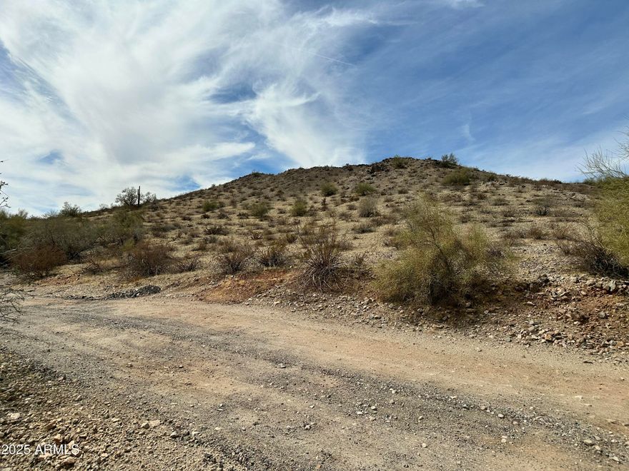 This spacious lot, nestled at the base of the majestic Estrella Mountains, presents breathtaking views of the downtown skyline. Imagine waking up to panoramic vistas and being just minutes away from Phoenix International Raceway and an array of hiking, biking, and horse riding trails, allowing for endless outdoor adventures. Golf enthusiasts will have access to nearby world-class golf courses. For those seeking tranquility, the nearby Estrella Mountain Park provides a serene escape, perfect for relaxation and recreation. Whether you're seeking a great investment or envisioning the construction of your dream home, this lot presents an exceptional opportunity. Use GPS coordinates: 33.3685585619843, -112.354235594721