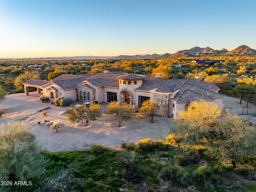 Set on 4.3 private acres in a premier location, this gated estate offers exceptional privacy w/sweeping desert & mountain views. A gated entry and pavered drive lead to a four car garage and fenced courtyard. Inside, soaring 14' ceilings frame a well designed split floor plan with refined architectural details and clear pride of ownership. The home features five bedrooms, five full baths, two half baths, an office, theater room, wet bar, and wine cellar. The kitchen is equipped with high end appliances and an oversized island ideal for entertaining. Expansive glass sliders open to a covered patio with fireplace, pool, and spa. Enjoy Arizona sunrises and sunsets from the rooftop deck. Located in the horse friendly Pinnacle Peak Ranchos community with room to add  equestrian amenities.