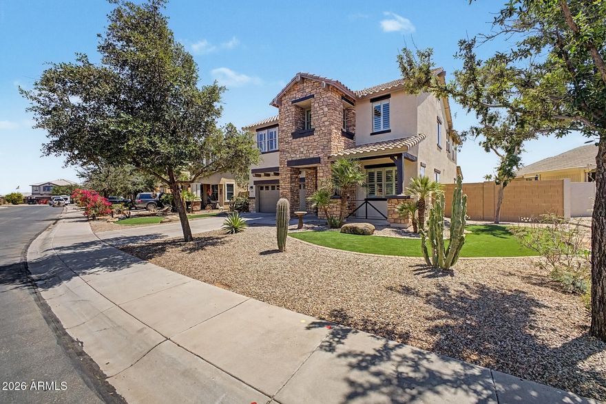 Welcome to your waterfront oasis! From the moment you arrive, you'll be captivated by the stunning curb appeal featuring two large synthetic grass areas, beautifully complemented by desert-friendly landscaping with mature cactus, palms, and trees. The freshly painted exterior is highlighted by gorgeous rock accents, giving this home a warm yet upscale presence.

Step inside to discover newly updated wood plank tile flooring that flows seamlessly throughout, paired with fresh interior paint that creates a bright and inviting atmosphere. Large windows fill the home with natural light and are enhanced with elegant vinyl shutters, while 9-foot ceilings add to the open, spacious feel.
As a former Hacienda model home, this residence offers a perfect blend of style, comfort, and thoughtful design--setting the stage for the exceptional living experience that continues throughout.
As you walk through the main hallway or pass through the elegant butler's pantry, you'll arrive at the true heart of the home--an impressive, fully remodeled kitchen, dining area, and family room highlighted by soaring 20+ foot ceilings. Expansive windows surround the space, flooding it with natural light and creating a bright, open atmosphere that's perfect for both everyday living and entertaining. The kitchen is beautifully appointed with nearly new 36" cabinetry, sleek stainless steel appliances, and an abundance of quartz countertops that provide generous workspace and gathering areas. The butler's pantry adds both function and style, offering additional cabinetry and quartz surfaces--ideal for hosting dinner parties or creating a sophisticated bar setup.

An elegant switchback staircase with iron railing and natural wood accents leads you to the second floor, where 9-foot ceilings continue the home's spacious feel and enhance airflow throughout. At the top of the stairs, you'll find a well-sized laundry room complete with a sink, countertop space, and a solar tube that fills the room with soft natural light. A nearby hallway offers additional upper and lower cabinetry with counter space--perfect for folding laundry or displaying décor.

Two generously sized secondary bedrooms are thoughtfully positioned and separated by a full bathroom.  Features include dual sinks and a separate area with tub shower combo  and glass enclosure.  The rear-facing room offers stunning views of the lake and nearby park.

On the opposite side of the home, a fourth bedroom also enjoys peaceful lake views. Just beyond, double doors lead you into the expansive primary suite--a true retreat. Surrounded by windows that invite in natural light, the space still offers ample wall area for furnishings and design. A convenient wet bar with sink, cabinetry, and mini fridge makes it perfect for a morning coffee station or evening unwind.
The luxurious en suite bathroom is designed for relaxation, featuring separate vanities with abundant counter space and storage, a large walk-in shower with a new glass enclosure, and a beautiful garden-style soaking tub framed by windows on three sides for natural light and ventilation. The suite is completed by an oversized walk-in closet spacious enough to rival a bedroom. Step outside to your breathtaking backyard oasis. A large covered patio provides the perfect setting to relax while overlooking the infinity-edge pool that visually blends into the serene lake beyond. With additional space ready for your personal touch--whether it's an outdoor kitchen with existing gas stub, expanded seating, or synthetic turf for play--this backyard is a true extension of the home's luxury living.Store your vehicles and toys in this 3 car garage with direct access to the back yard.
Built with 2x6 construction for enhanced energy efficiency and comfort, and extensively remodeled just 2½ years ago, this home offers the feel of nearly new construction. Waterfront luxury like this is rare--and it won't last long.
Professional photos coming May 2nd