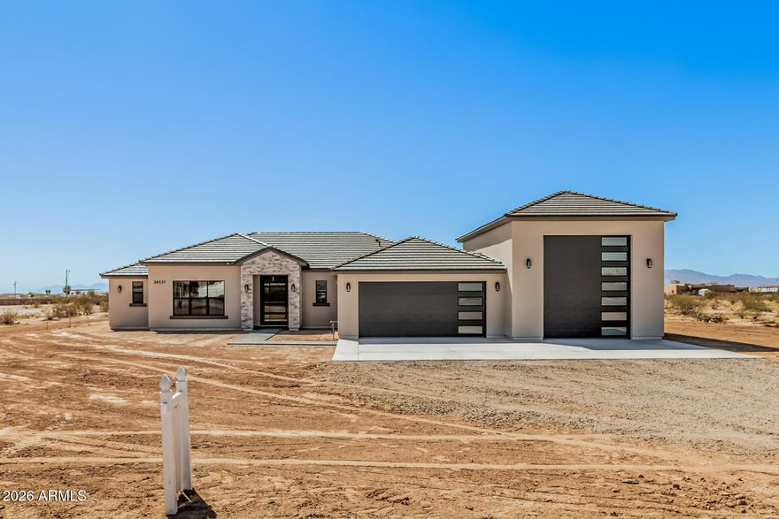 Brand new construction in Wittmann! This stunning 4BD/3BA, 2,392 SF home on 1 acre checks every box. Step through a modern pivot glass door onto sleek 32x32 tile floors. The chef's kitchen dazzles with two-tone ceiling-height cabinets, lighted glass uppers, built-in cooktop, and separate microwave & oven -- plus a pantry with wine cooler. Two primary suites each feature private baths, with the main offering a standalone soaking tub and tiled shower. All bedrooms include built-in closet organizers. LED-lit mirrors throughout. Convenient mudroom entry. The oversized RV garage features epoxy floors. Modern luxury meets wide open space -- this one won't last!