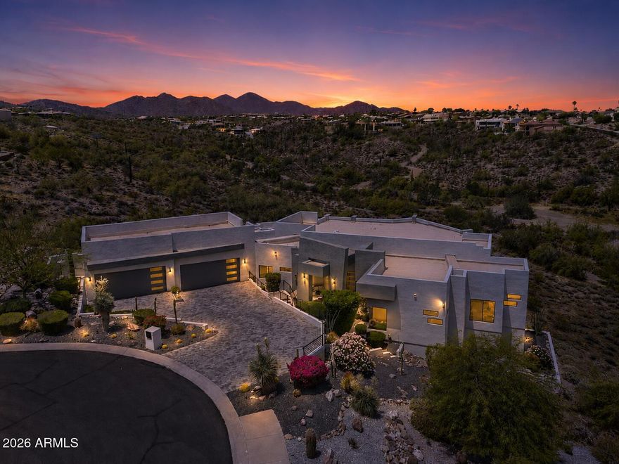 Pristine contemporary estate nestled on a private acre lot within an exclusive gated enclave, capturing breathtaking Mountain views & backing to a serene open wash. Designed for seamless indoor/outdoor living, the open great room showcases wood flooring, soaring ceilings, modern finishes, gas fireplace, wet bar, & dramatic pocket slider that fully retreats into the wall. The chef's kitchen is both functional & stunning, featuring professional stainless appliances (gas range), custom cabinetry, quartz counters, & waterfall island w/ seating. A desirable split floorplan offers privacy, anchored by a luxurious primary retreat w/ sitting area & mountain views,oversized walk-in closet, & spa-inspired bath w/ dual floating vanities, soaking tub, & walk-through shower. Three additional  (MORE) well-appointed bedrooms, including 2 en-suite, provide ideal accommodations for family/guests. Resort-style backyard w/ covered patios, BBQ area, & heated infinity-edge pool/spa. Additional features:4-car garage w/ epoxy floors & EV charger, power shades, designer lighting, & spacious laundry room.