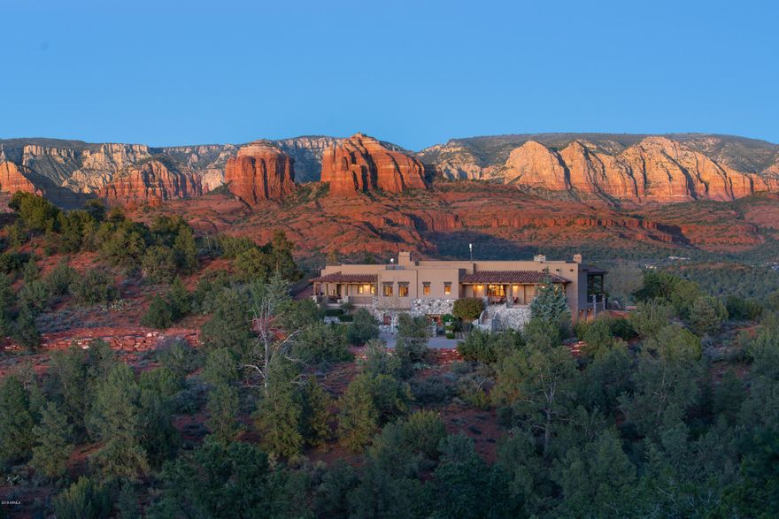 Perched on a hilltop with elevated red rock views, this custom masterpiece designed perfectly for the two+ acres, backs to national forest and state park land, offering its new owner ultimate privacy and unforgettable panoramic views. Quality construction for the discriminating buyer, soft southwest contemporary architecture, 5,840 square feet indoors with a warm and inviting feel. Create lasting memories, experience serenity, year-round outdoor living, captivating views and a luxury home that can host intimate and grand gatherings. The cascading waterfall, a heated pool, hot tub, golf putting green, outdoor entertaining patios & outdoor built-in kitchen/barbecue, cozy outdoor fireplace, and fenced wall of yellow roses adds to the ambiance of resort style living... Lovers of nature and healthy-conscious living will appreciate walking right outside your home onto your private 
gated entry stepping into miles of national forest trails, Oak Creek, and Sedona's Red Rock State Park. 

MAIN LIVING LEVEL: Impeccably maintained, the main level of the home boasts a gourmet kitchen equipped with a Wolf range & oven, and brand new Wolf cabinet-mount oven, Sub-zero refrigerator, granite counter-tops with an island, breakfast bar, breakfast dining nook, gorgeous alder wood cabinetry, a walk-in pantry, beverage wet bar with dual temperature-controlled wine refrigerator for reds and whites, an ice-maker, sink, and beautiful cabinetry to showcase your collection of beautiful stemware. Open great room floor-plan with a fireplace and walls of windows for that indoor/outdoor living experience. A formal dining room and separate sitting room for gatherings. Master bedroom suite welcomes the ambiance and tranquility from the sounds coming from the waterfall in your back yard. Lush master bath with soaking tub, walk-in shower, dual vanities, water closet with a bonus bidet, and a coveted walk-in closet with built-in custom cabinets and shelving  compensating for the desired space on most wish lists. A second (2nd) spacious master bedroom & bathroom suite; third (3rd) bedroom with a private balcony; large office with custom alder wood built-in cabinets a custom stained-glass door adding to the ambiance of an inspiring office space; a luxurious laundry room...all on the main living level.

LOWER LEVEL: The lower level includes an elite fitness room equipped with professional-grade fitness equipment that can be purchased on a separate bill of sale (no commissions are paid to agents). For the wine connoisseur, a temperature-controlled wine room + shelving.  A four (4) car garage with built-in cabinetry and bonus storage room. 

See Supplemental Information Attached To Documents in MLS!