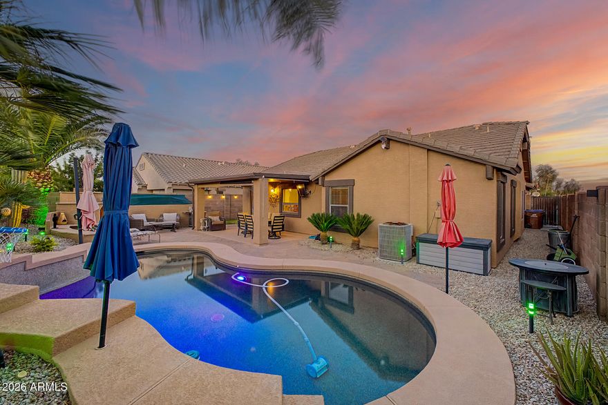 RESORT-STYLE BACKYARD, SPARKLING HEATED POOL, PROFESSIONAL PUTTING GREEN & FIRE PIT. Welcome home to this beautifully maintained 3-bedroom, 2-bathroom home in the highly sought-after Johnson Ranch community. This popular open floor plan features vaulted ceilings, abundant natural light, and a split-bedroom layout for added privacy. The kitchen opens to the main living area and offers granite countertops, a large island, stainless steel appliances, and ample storage. Step outside to your private backyard retreat featuring a sparkling heated pool, professional putting green, covered patio, and a cozy fire pit area, perfect for YEAR- ROUND entertaining, relaxing, and enjoying Arizona living.