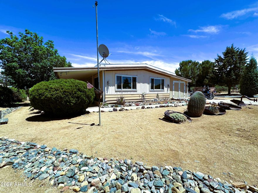This beautifully landscaped property, with a 2 bedroom, 2 bath doublewide home, is located on a little under a 1/2 acre.  The property features a well maintained,1,248 sq.ft, home, with an open floor plan.  This home has a unique feature that has kept this home in excellent condition, an additional roof built over the home to protect the inside from any water damage or leaks. 
The property has it all... an RV Gate, RV hook ups, an attached 220V insulated workshop, extra storage, two outside storage sheds, a framed in garden space (13 X 24 ft: See Pictures), a small animal coop, a large pear tree that bears a mighty harvest come July and August, huge pines, and a gathering place for great evenings around the fire.  New double paned windows were installed in the living room and in the storage and workshop areas.  A new 1000-gallon septic tank and leach field were installed in 2015. Come and enjoy the coolness and peacefulness of Cordes Lakes, located within easy commutes to Phoenix, Prescott, and to the north and beyond.