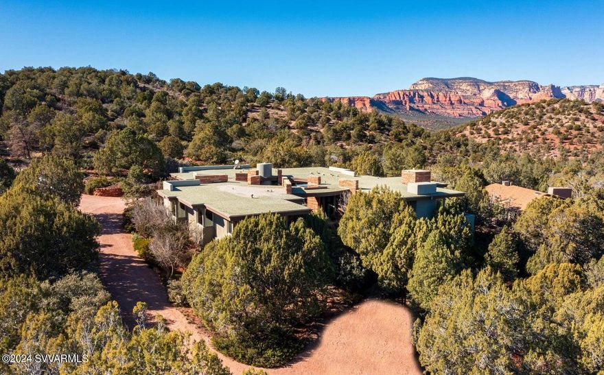 Signature Design Group home on 2.5 acres bordering National Forest, with unsurpassed panoramic Red Rock Views and ultimate privacy. -
Securely located on the cal-du-sac of a high-end gated community this extremely private home is set high into the hillside, perfectly built to be part of the terrain and toward big northern and eastern views from Summit, Chimney Rock, Thunder Mountain and Lizard Head to Boynton Canyon and Bear Mountain. - The main house with living room open to dining and high-end kitchen - all three built around a large three-sided fireplace - features the master bedroom suite, a bonus room currently used as gym, and a powder room. The soothing sound of a water feature outside the master bedroom attracts a large variety of wildlife.  Connected by a covered circular walk way, the casita offers two large guest bedrooms, a bath and a bonus room. One of the bedrooms and the bonus room are currently used as offices. -
Both main house and casita are built around an enchanted round court yard with wood burning fire place, outdoor kitchen, spa and a large view window. The well designed pond with waterfall contributes to the ambiance. 
Large windows and multiple outdoor sitting areas allow indoors and outdoor to blend seamlessly and facilitate the all year round indoor-outdoor Sedona lifestyle. 
Observe wildlife from the privacy of your home, watch dramatic sunrises and sunsets reflected on the Red Rocks, curl up in front of one of the fireplaces, delight in Sedona's starry nights while soaking in the hot tub, listen to the sound of running water, entertain friends or start hiking and biking endless miles of trails from your home.-
In spite of living next to National Forest it is only a short drive to restaurants, shops, entertainment and all amenities of town. Just a few minutes drive from the Enchantment Resort with its world renowned luxury Spa Miiamo and the Seven Canyons private golf club. 
Single level with only 2 steps down to living room and from garage.
Easy to take care of landscaping and lots of storage space.
Plenty of room for a pool.
No vacation rentals possible.