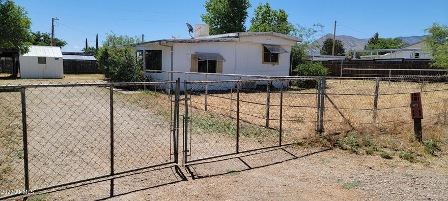 If you are looking for affordable housing, look no further! This cute home on a quiet street is just what you are looking for. There is a 1973 mobile home with a large add on. The square footage includes both. There is also a carport with a shed next to it for storage. There is an RV Gate as well. On the 2nd little lot included within the fence there is a trailer and a shed that provide extra storage. These will remain with the property. This is an AS IS sale.