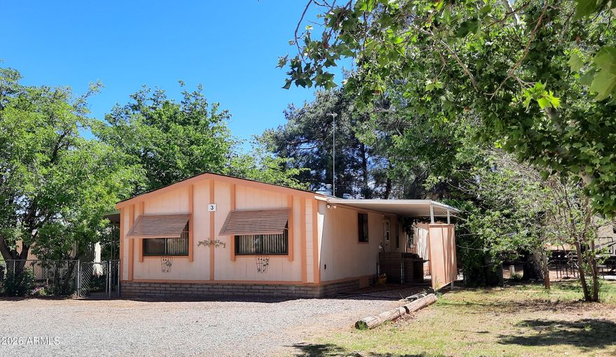 Come home to an oasis in town! Upon entering Thunderbird MH Park, Follow the red arrows to your new home! Just past the office, take the first left, then follow  the road to the end where house #3 is located. The cul-de-sac is quiet and peaceful. Home rests on a solid block foundation.  Beautifully landscaped lot in a secluded location and yard that is enclosed by a chainlink fence.  There are large shade trees, a peach tree and a fig tree that produce amazing fruit! A huge jasmine vine shades the carport.  The covered front porch leads to a large addition - this could be used as an office or an extra bedroom.  New hot water heater in 2025. All major AC components have been replaced.  Sprinkler system in front yard. Two sheds to store tools and extras.
