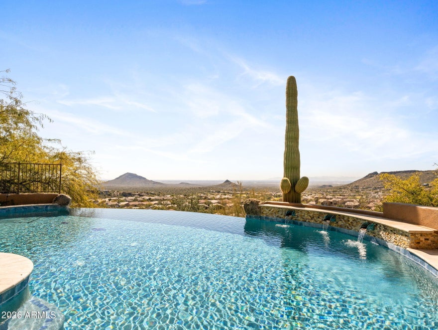 Perched high within the prestigious guard-gated FireRock Country Club, this meticulously maintained luxury residence invites you to surround yourself in panoramic views from every main living area, elevated above the sweeping valley below. Walls of tall butted-glass windows frame the desert, mountain, and city-light vistas while flooding the home with abundant natural light and seamlessly blending indoor and outdoor living.
The thoughtfully designed floorplan is anchored by a chef's kitchen that opens effortlessly to the family room and breakfast area, all oriented toward the deep covered patio and its breathtaking outlook. Culinary enthusiasts will appreciate the Wolf double ovens with 6-burner cooktop and griddle, Sub-Zero refrigerator, Sub-Zero 75-bottle wine cooler.  Elegant (Cont) Cantera stone accents, Barrel-vault ceilings, Cantera fireplaces and mantles, whole-house surround sound, and new custom shutters enhance the home's sophisticated character, while bamboo hardwood flooring warms the bedroom spaces.
Every bedroom offers the comfort of an en-suite bath, each appointed with Toto toilets and zero-entry showers. A spacious guest suite provides ideal accommodations for visitors or multigenerational living, delivering privacy without sacrificing luxury.
Step outside to a true resort experience. A newly finished negative-edge pool appears to spill into the valley views, complemented by new pool equipment, a heated spa, fire pit, putting green, and a wide variety of seating areas designed to capture Arizona's stunning sunrises and sunsets.
Additional highlights include two separate 2-car air-conditioned garages, all new HVAC systems installed in 2023, and impeccable pride of ownership throughout.
Residents of FireRock Country Club enjoy a celebrated 18-hole golf course, vibrant golf culture, and a sports club featuring a fitness center, tennis courts, and pickleball courts. A lively calendar of dining, social, and racquet events accompanies a comprehensive $29M community reinvestment  creating not just a home, but a refined desert lifestyle in one of Fountain Hills' most sought-after communities.