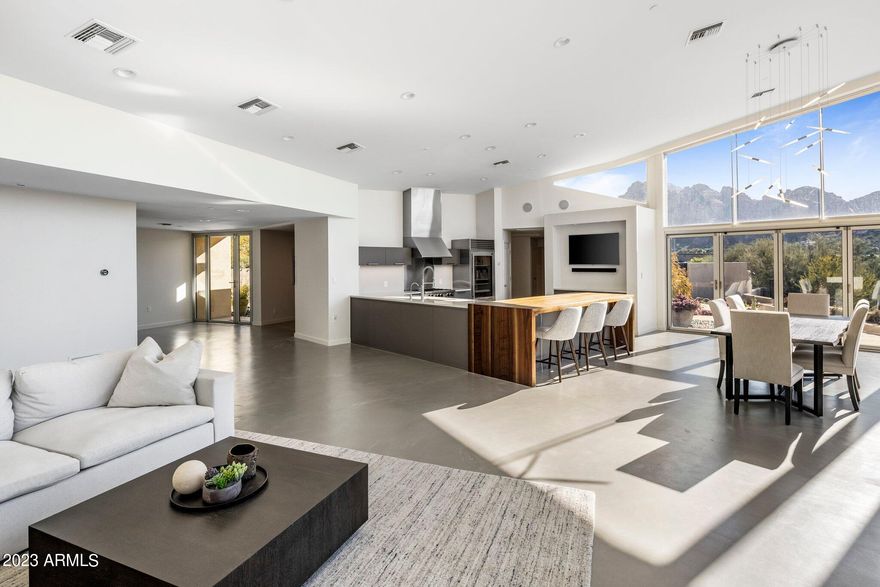 This spectacular hillside modern home is a stunning example of contemporary design, featuring clean lines and an open floor plan. Remodeled in 2021 with no detail overlooked. Jaw dropping views of Camelback, Papago and South Mountain with twinkling city lights create the perfect ambience. The spacious living room boasts high ceilings and plenty of natural light, with large windows that offer views of the Desert Botanical inspired landscape. The 30+ feet accordian doors and concrete flooring create a dramatic effect and flawless indoor/outdoor living. The kitchen is a chef's dream, with sleek Sub-Zero, Bosch and Blue Star appliances, ample counter space, and a walnut waterfall island that provides a convenient spot for meal prep and casual dining. The primary suite is the perfect getaway with an abundance of natural light pouring in through the floor to ceiling windows and has a private patio to relax and unwind. The spa-like primary bathroom features dual vanities, deep soaking tub and walk-in shower.   The three guest bedrooms are also generously sized with spacious clothing closets.  Smart home technology for convenience and easy living. The backyard is fitted with beautiful synthetic grass, sparkling pool, built-in BBQ and plenty of patio space to sit back and enjoy the breathtaking views!