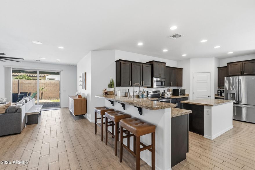 Santa Rita Gated Living! Situated on a corner lot directly across from the community green space, this North Phoenix home offers a bright & open layout with high ceilings & abundant natural light throughout. The kitchen features a large center island, granite countertops, stainless steel appliances, walk-in pantry, breakfast bar seating & eat-in dining area. It flows seamlessly into the living space with wood-look flooring, multiple windows & a large sliding door for indoor-outdoor living. The primary suite is generously sized with an ensuite offering dual vanities & a walk-in shower. The backyard is designed for enjoyment with a covered patio, built-in BBQ, natural gas fire pit & grassy area. A 2-car garage with built-in cabinetry adds extra storage, all within a gated community setting.
