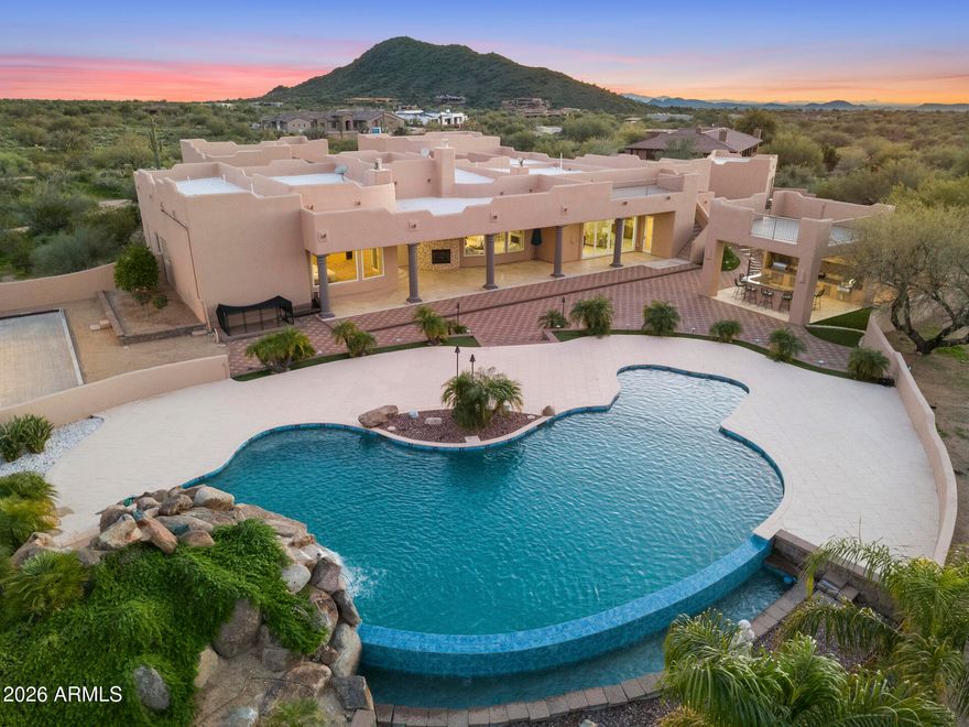 Priced $259K Below Recent Appraised Value! Experience Elevated Desert Living in this Custom Southwestern Estate set on nearly 3 Private acres in a Premier North Scottsdale setting, with stunning Mountain & Sunset Views. The 4,859 sq ft main residence is complemented by a 983 sq ft detached Casita, ideal for guests or extended stays. A Gated Entry leads to an expansive Paver Drive & exceptional Garage amenities including an attached extended-length 3-car Garage + RV Garage + 1 Detached Garage, accommodating up to 8 vehicles. Inside, polished Travertine floors, newer Custom Windows, Illuminated Recessed Ceilings, and a 2-way Fireplace create a Refined Ambiance. Resort-style grounds feature a dramatic Elevated Pool with Waterfall, Grotto, Hidden Slide, Outdoor Kitchen with View Deck, Fireplace, Patios & Bocce Court - perfect for Luxury Entertaining! - Designed for Elevated Living and Grand-Scale Entertaining, this Estate blends timeless Southwestern architecture with Modern Luxury. The Open-Concept layout seamlessly connects Formal and Casual spaces, Enhanced by Abundant Natural Light, Illuminated Recessed Ceilings, and Refined Finishes throughout. The Fully Reimagined Chef's Kitchen is a Showpiece, offering a Large Center Island, Granite Countertops with Full-Height Backsplash, custom Flat-Panel Cabinetry with Integrated Display Niches, Over & Under-Cabinet Lighting, and Premium Sub-Zero and Wolf Appliances including Professional Built-in Refrigerator/Freezer & Wine Storage, Wall Ovens, Convection Cooktop, Prep Sink, and Peninsula Seating. The two bar areas and formal handcrafted built-in dining hutch feature stunning, distinctive quartzite countertops. The Primary Suite is a Private Retreat Featuring a Fireplace, Motorized Blinds, Custom Built-in Wardrobe and Entertainment Unit, and a Spa-Inspired Bath with Soaking Tub, Spacious Walk-in Shower, Dual Vanities, and Expansive Custom His-and-Hers Closet Systems with Island Storage. Secondary Baths reflect the same Elevated Craftsmanship and Design including Marble Counters. Outdoor Living Rivals a Private Resort with an Elevated Pool, Oversized Waterfall, Grotto, and Concealed Slide! A Freestanding Gazebo offers an Upper-Level View Deck and a Fully Equipped Outdoor Kitchen below with Multiple Grills, Range/Oven, Fridge, Bar Seating, Ceiling Fans, and TV. Additional Covered Patios with Travertine Flooring and Fireplace extend the Living Space Outdoors, while a Bocce Ball Court completes this exceptional North Scottsdale offering!
