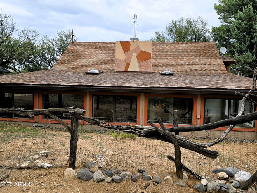 Artists' Dream home with original art from natural Southwest materials incorporated into the functional design and situated on 2.67 quiet acres close to the Prescott National Forest. This property is fenced and cross fenced with two shop buildings, a chicken coop and goat barn. Located In the beautiful Verde Valley, Camp Verde, AZ. This rural country home is defined by its spaciousness, privacy, and the opportunity for a self-sufficient lifestyle, including the keeping of animals. The property's size provides ample room for various projects, and its rural location comes with fewer restrictions, especially regarding animal ownership. No HOA or CCR's,  Yavapai County requirements apply.  This country home combines timeless, rustic charm with modern comforts. The earth berm architecture built partly underground, provides insulated coolness in the summer & warmth in winter months, incorporating, sustainability & conservation of energy, giving efficiency & charm. With its many windows, stone walkways and walls It creates an effortless transition between indoor & outdoor living. The exterior features 2/6 framing, cement, stone, & brick.
The family living room serves as a central hub for gathering, with flagstone fireplace, 18 ft high vaulted ceilings, generous space, and an eat-in dining area.
 Adaptable floor plan interior spaces are large mostly open, and the layout can be flexible, with rooms suitable for a home office, hobby space, work out or guest accommodations. Architectural elements like custom stair railings to an upstairs loft create a warm, inviting feeling. Flooring consists of pinewood plank, tile, and concrete, with a carpeted upper loft give durability and are easy to clean, a major benefit for animal owners.
The land is large enough to offer significant privacy while still being manageable for a family. The acreage provides the perfect buffer from neighbors and a blank canvas for customization. Native trimmed mesquites give some privacy with some shrubs and flagstone walkway to the front door of the home. 
 Room for customization, unlike many urban or suburban homes, a rural home has fewer restrictions, giving you the freedom to build a workshop, a separate guest house, or add other structures, that conform with Yavapai County regulations and RCU-2 AC zoning. 
Relatively convenient access to services, while in a rural country setting, it is approximately 15 minutes from the town of Camp Verde for shopping, schools, and hospital. The roads are paved and maintained by the county and town. There is a 20-foot dirt easement road to the entry gate. There is a caretaker on the premises, possibilities are available to keep the caretaker.
