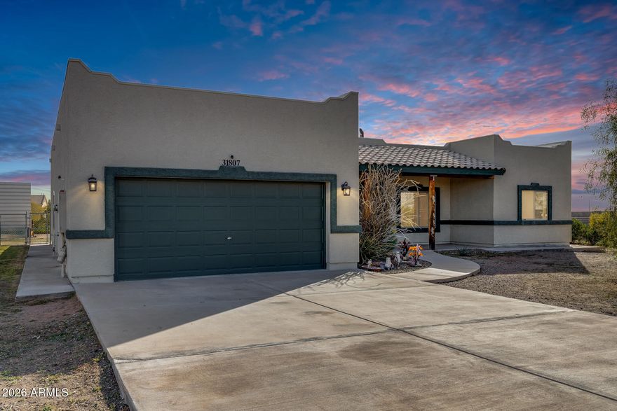 Wide-open space, desert serenity, and total freedom—no HOA! This updated 3-bed, 2-bath home sits on over an acre with breathtaking White Tank Mountain views, offering quiet living and endless possibilities. Enjoy a spacious great room, a split primary suite with walk-in closet and full bath, and a functional kitchen with pantry, ample cabinetry, and refrigerator included. Recent upgrades include a new roof (2020) and exterior paint (2022). Outside, you'll find an extended driveway, RV parking with RV cover, and a concrete pad—perfect for a shop or storage. Covered front and back porches invite you to relax and take in the desert views. Ideal for equestrian use, expansion, or custom projects, this property delivers privacy, flexibility, and room to grow.