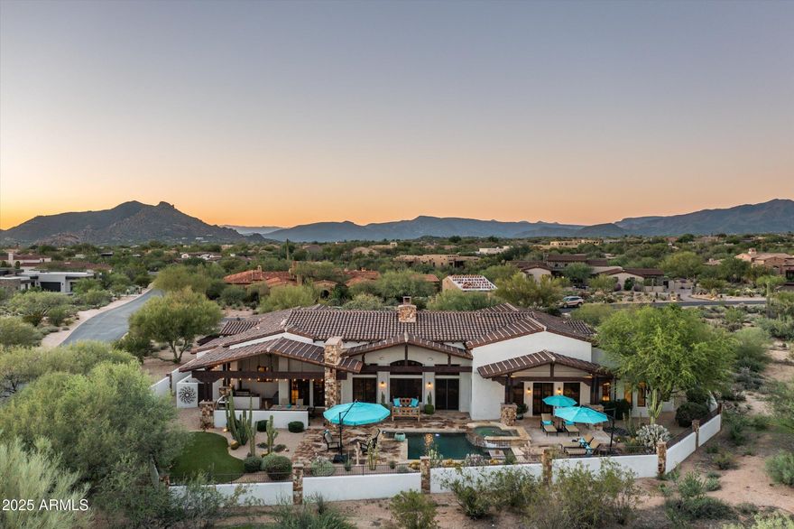 Nestled within the prestigious guard-gated community of Whisper Rock Estates, this elegant ranch-inspired residence sits on a south-facing 1.2-acre lot offering exceptional privacy. Designed with a true open-concept floor plan, the home showcases impeccable craftsmanship and thoughtfully designed spaces for effortless indoor-outdoor living. The expansive great room features a striking floor-to-ceiling stone fireplace and a full-service wet bar. The gourmet kitchen is complemented by a butler's area and temperature-controlled wine room. The primary retreat boasts a spacious sitting area, an impressive bath and dressing closet, and direct access to the resort-style backyard with pool and spa. Outside, enjoy true Arizona living with a fully equipped outdoor kitchen, covered patio, fireplace, and heated pool and spa. Three additional guest suites, an executive office, a versatile den/media room, and 4 car garage complete the estate.
