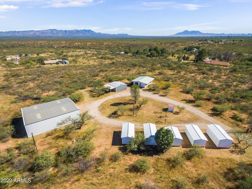 Calling all hobbyists, auto enthusiasts, tinkerers, craftspeople of all sorts! Don't miss this chance to have your very own 2000 sf steel workshop and five (Count them! Five!) durable storage sheds, on nine acres of land with mountain views! Simplify your life by living in the tiny home with one bathroom and kitchenette, solidly refurbished with metal box-tubing siding and metal roof. Separate garage includes RV hookup and flush-out connection.  Private well with two pressure tanks!  Workshop includes 4-post car lift and separate electric meter; wired for 220... use your welders and air compressors! Endless possibilities just waiting for you to make it your own!