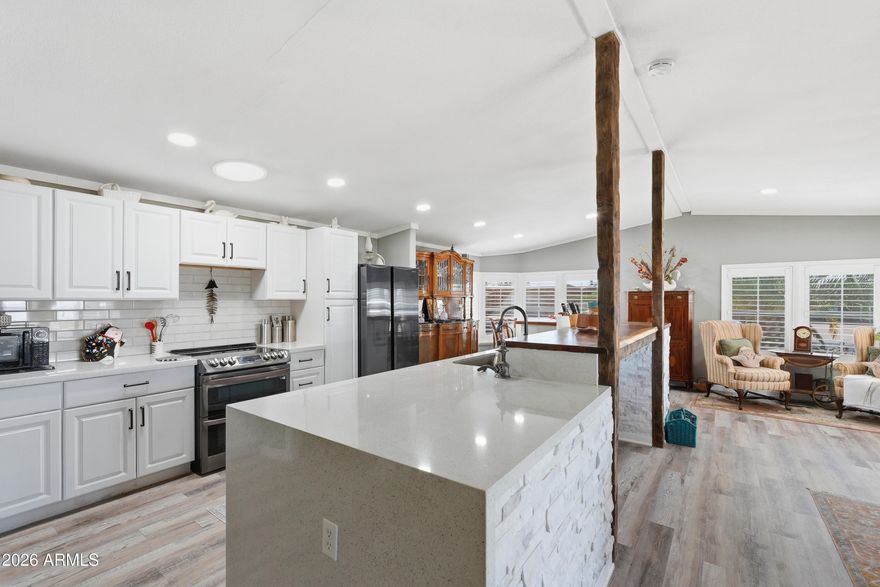Fully remodeled in 2021, this one-of-a-kind manufactured home in the heart of Sun Lakes features extensive upgrades throughout. The kitchen showcases waterfall quartz countertops, a live-edge bar, and black stainless steel appliances,  and dishwasher (2022), plus matching refrigerator, washer, and dryer. Interior highlights include skylights, crown molding, plantation shutters, vinyl flooring, and updated bathrooms with a beautiful walk-in shower in the primary suite. Major improvements include a new roof and HVAC in 2024, along with updated plumbing, insulation,  Added garage and office space, golf cart/storage patio, and fully walled backyard with turf, raised planters, and orange and lemon trees.