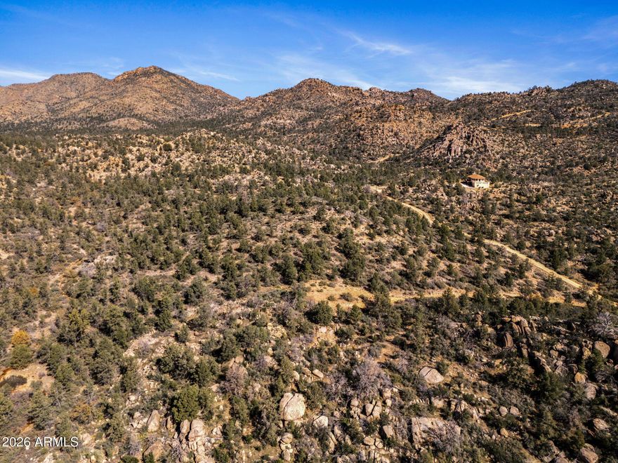 MAGNIFICENT PROPERTY WITH GORGEOUS TREES AND STUNNING BOULDER FORMATIONS! This impressive property is truly one of a kind. Seasonal creek runs along the west side. The varied topography brings so much character to the scenic landscape. Enjoy views of iconic Rocky Boy Peak. What a feast for the eyes! Driveway leads up to a flat, level area perfect for a house pad. A gated community and well-maintained roads provide privacy with easy access. Just 26 minutes from paved road to the middle of nowhere. It's hard to believe but it's absolutely true! Blue skies, fresh air and cool mountain breezes await. Just about an hour from Wickenburg and Prescott, amenities are close but not too close. Wildlife and hiking opportunities abound. **1,800 min sq ft build applies.