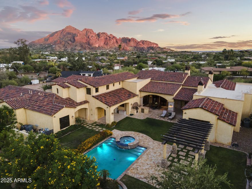 This exquisite hillside home built by renowned luxury builder Bedbrock Developer is perfectly positioned to capture stunning views of Camelback Mountain. Surrounded by a privacy wall, it showcases Mediterranean design such as Venetian plaster, terracotta roof tiles, arched entryways, Wrought iron accents & remote entry gate. Home features soaring ceilings with exposed wood beams and rich natural stone. The gourmet kitchen opens to a spacious family room with wet bar, wine cellar, primary suite with large walk-in closet, media room, formal dining room & living room w/French doors opening to resort style backyard & separate guest suite. The outside is a true retreat complete with a sparkling pool and spa, a mini soccer field, basketball/sport court and multiple patios. Prime location! The resort-style backyard is a true retreat and perfect for enjoying Arizona's year-round sunshine. Whether hosting guests or enjoying quiet moments, this extraordinary home offers a luxurious lifestyle framed by unparalleled mountain views.