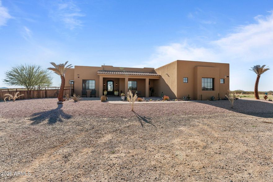 This fully permitted equestrian estate is thoughtfully designed for functionality, privacy &  serious horse use, offering direct access to Arizona Trust land & sweeping mountain views. Graveled road, A private electric gated entry welcomes you into the property, accented by attractive landscaping and well-planned improvements throughout. The arena is currently set up for barrel racing but is sized to accommodate a full team roping arena with minimal additions, complete with hauled-in sand & a hot walker. The equine facilities are extensive & built for efficiency, featuring 8 covered 60' x 40' pens & 4 additional uncovered 60' by 40' pens with solar lighting, automatic waterers, feeders, along with a large barn (approximately 14,000 sq ft) includes (12)15' x 30' stalls 2 tack rooms1 equipped with a bathroom a spacious covered hangar-style structure that provides ample shaded space for saddling, staging, &  daily operations. An additional 10 acres is available for purchase, offering expanded arenas, pens, shop, RV hookup & potential for future improvements.
The property is serviced by a shared well with approximately 3,000 gallons of storage and includes a convenient 50-amp RV hookup located at the house power panel.
The residence offers four bedrooms and three and one-half bathrooms with a well-designed layout. The primary suite features double sinks, a walk-in closet, a soaking tub, and a separate shower. Guest accommodations include a private guest bedroom with its own tub, shower, and walk-in closet, as well as a Jack-and-Jill bathroom with double sinks, tub, and shower. Additional interior features include an all-electric setup, formal dining room, kitchen dining area, pantry, ice bin, wood-accented ceilings with exposed beams, built-in speakers throughout, exterior security cameras, and a laundry room with sink. Outdoor living is elevated with a rooftop hot tub and view deck, a spacious backyard, and mature orange, lemon, and lime treescreating a rare blend of comfort, functionality, and true equestrian lifestyle living.