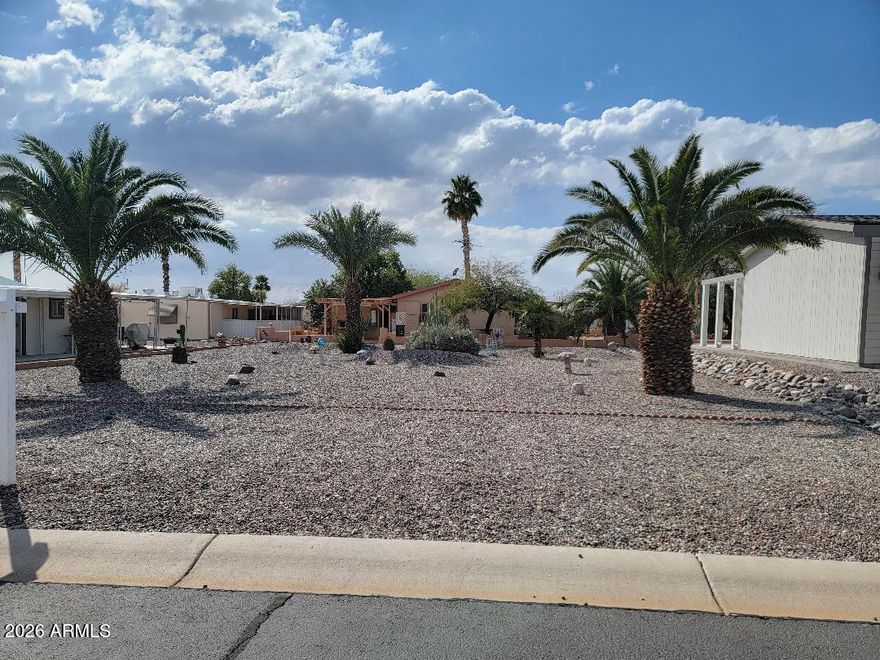 This is a beautifully landscaped lot with all utilities to the property line. YOU OWN THE LAND HERE! The home next door at 3704 Kansas is also for sale  at an additional fee and can be purchased together at a discount for the two. Could put a garage on this lot or a new home.
This lot has wonderful palm trees and beautiful desert scape and rock! Enjoy all that Florence Gardens has to offer with golf course, pickleball, heated pools and spas, craft rooms, billiards hall, library, work out room and more!!