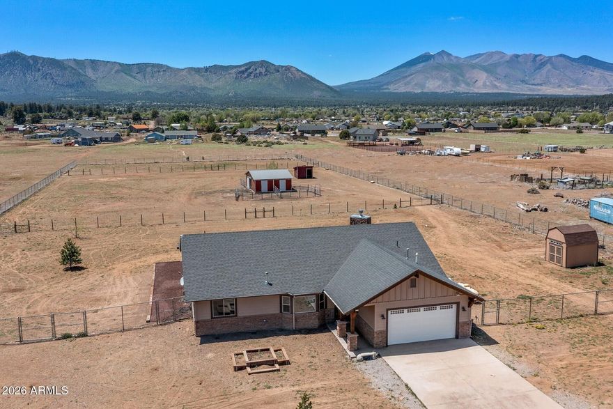Experience the beauty of Northern Arizona living with this exceptional horse property in the desirable Doney Park area of Flagstaff. Surrounded by breathtaking San Francisco Peak views and open skies, the property features a beautiful stable complete with three 12X12 horse stalls, and a 12X12 tack room making it ideal for equestrian enthusiasts. Inside, rich dark wood trim flows throughout the home, creating a cozy atmosphere. The thoughtfully designed open floor plan offers an expansive feel without sacrificing comfort, creating spaces that are both sophisticated and welcoming. Natural light pours through the home, highlighting the intricate details and craftsmanship found in every room. Featuring vaulted ceilings, recessed lighting, and wood accents throughout brings a touch of warmth to this one of a kind home. Step outside under the covered porch to discover an unforgettable stunning handcrafted wooden picnic table anchored by an inviting outdoor fireplace creating the ultimate setting for celebrations, dinners under the stars, or peaceful mornings in the mountain air. Whether you're entertaining guests, relaxing with family, or simply taking in the peaceful surroundings, the seamless indoor-outdoor flow allows you to fully appreciate the stunning San Francisco Peaks backdrop and tranquil setting.