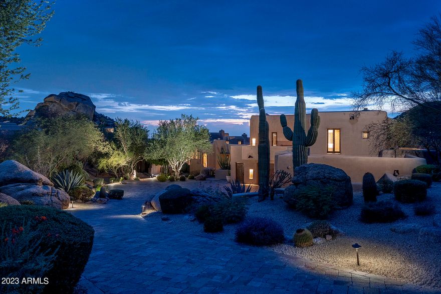 Abundant nature and distinguished architecture come together at La Casa Sobre La Laguna (the house over the creek).  Lovingly designed by master adobe architect Bill Tull, this home is beautifully positioned to take in staggering views in every direction, mountain, golf course and dramatic boulder outcroppings.  The palatte is cool and welcoming; pristine flagstone floors, stately vegas, delicate latilla ceilings.  Home is nestled into an elevated lot, built over a desert stream and the romance is enhanced by nine wood burning fireplaces, numerous outdoor entertaining areas orientated to take in sunsets.  Floorplan is thoughtful; generous living spaces, sophisticated dining area and a kitchen that is well appointed and intimate at the same time. Primary suite feels like a private retreat with generous closet space, two full baths, exercise room and private study or office.  Main living space has fabulous media room / bar that opens to infinity edge pool and spa.  Two private guest houses, each offering walk in closets, kitchenettes, full baths and balconies.  Rare four car garage and ample storage space.  This Sonoran desert estate in The Boulders is nothing short of extraordinary.