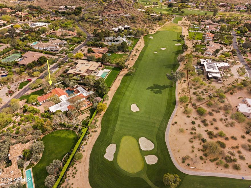 A rare offering on the 4th fairway of Paradise Valley Country Club, this 6604 sf desert/modern - extensively remodeled (GM Hunt 2013) estate blends timeless character with a refined modern edge. Highlighting a private courtyard pool, the home features Saltillo and wood floors, floating beam ceilings, and restored antique doors. Framed by views of Mummy Mountain in the front and the Phx Mountain Preserve beyond, the home sits along the golf course, offering a picturesque setting. The backyard is designed for both entertaining and everyday living, w/multiple patio spaces, expansive lawn, mature trees, and a curated vegetable garden. The primary suite features vaulted ceilings, a spacious bathroom, 2 water closets and large dressing room. The reimagined kitchen showcases mid-century modern... influence with Viking appliances, double ovens, a prep kitchen, and ample storage. Multiple living areas open seamlessly to lush grounds with olive and citrus trees, grass, and a brick patio w/ firepit. Three additional bedrooms, an office/library, 4 car garages + flexible spaces offer versatility. A warm, architecturally rich property in one of Paradise Valley's most coveted locations.