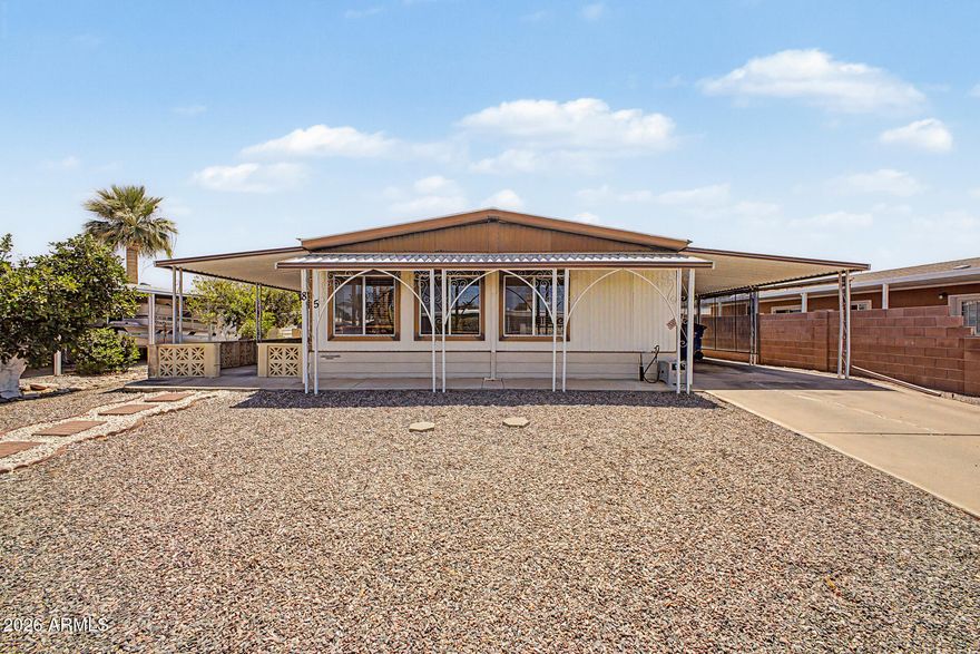 Seize the chance to own this charming 2-bedroom, 2-bath manufactured home in the adult Community of Village Grove. You're greeted by an attached carport, a low-maintenance desert landscape, and a sizeable covered patio for outdoor relaxation. The serene living room features wood-panel walls, blinds, and soft carpeting underfoot. Cook delicious meals in the well-appointed kitchen, equipped with ample cabinetry, built-in appliances, a pantry, and a two-tier peninsula with a breakfast bar. The cozy main bedroom includes a private bathroom for added comfort. The sizeable backyard offers storage sheds and ample space for activities. The Community boasts a refreshing pool and spa for cooling down on hot days.