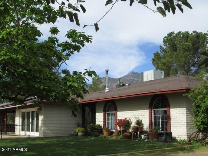 This is a MUST SEE 3 bd/2ba home! There are many fantastic amenities and unique qualities that you will enjoy. These include an outdoor fire ring, front and back patio areas for entertaining and an abundance of fruit trees. The interior of the home boasts built-in bookcases, A/C, a huge double pantry, double paned windows, a wood burning fireplace and amazing  artistry carved into the interior doors. There is plenty of room for extra vehicles or RV's on this 2+ acres that includes a 1+ car detached garage/workshop with full bathroom, RV hookup and a 2 car carport. This beautiful home is fully fenced and tucked in among huge pine trees with mountain views. Call for a private viewing today!