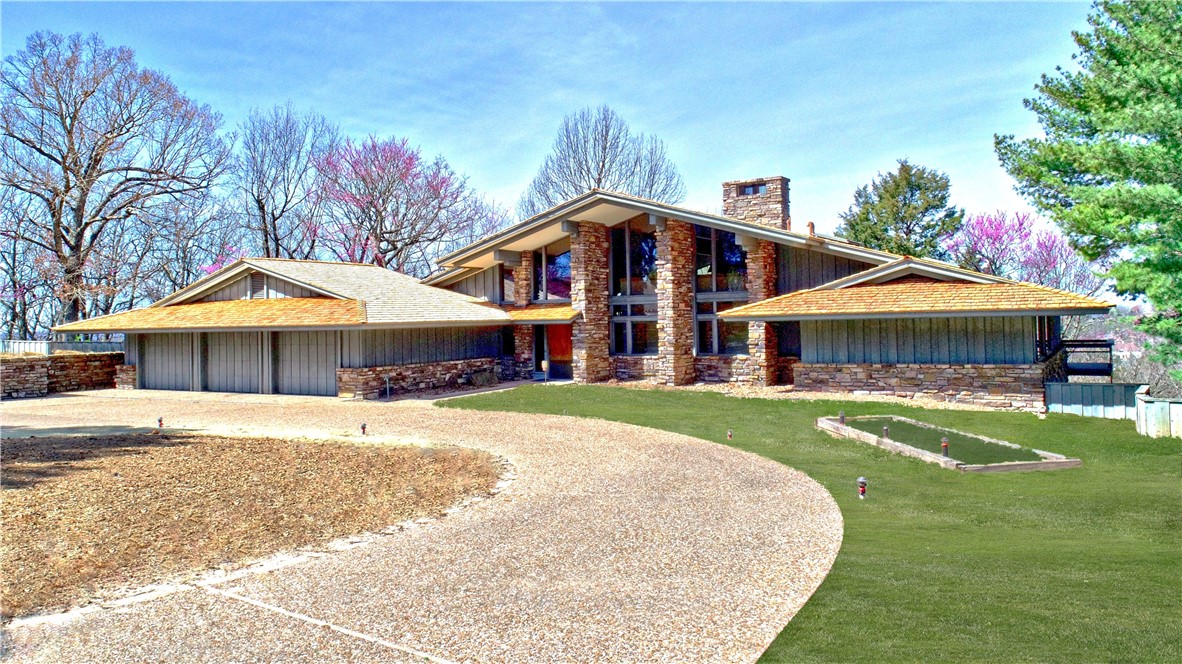 Discover an architectural masterpiece in this E Fay Jones inspired 3400+ sq. ft, 3-bedroom, 3 1/2-bath home with spectacular views. Centered in a cul-de-sac at the top of Hyland Park Phase II, this truly exceptional home was built by Jerry LaBounty, the renowned general contractor for E. Fay Jones, whose legacy includes Thorncrown and Cooper Memorial Chapels. Expansive walls of windows at the front and back flood the home with natural light, framing breathtaking sunrise and sunset views. The home is structurally engineered with steel beams and piers for enduring strength. The primary suite offers the ultimate retreat with separate his-and-her bathrooms and walk-in closets. A striking floating steel staircase leads to a versatile loft space. Outdoors, over 2,000 sq. ft. of aggregate concrete patio provides a stunning backdrop for entertaining and relaxation. A rare fusion of architectural brilliance, this home is a true work of art.