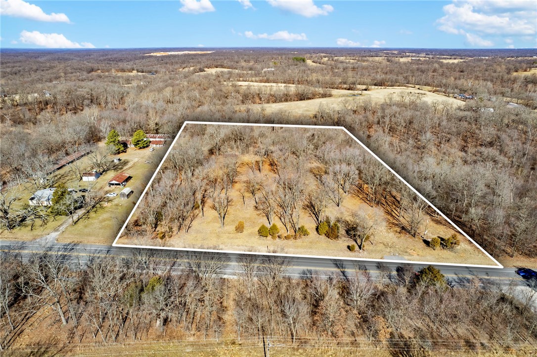 Prime location for Commercial-Residential or Agricultural! Imagine tossing another log on the fire in your future build tucked away with total privacy but so close to I-49 bypass to get where you need to go quickly. Property is located on a serene private 7 acre lot right off of highway 72. This ideal location would be perfect for a business as well! Lot has been cleared of dead trees & brush. Asphalt entrance already on property, water meter set. Ready for electricity on same side of the highway. Rare find! Located just 13 miles from Walmart Home offices! Approximately 2-3 minutes from the new bypass. Over 7 acres of wooded and gently sloping land - this is a builder's dream! Don't miss out on this opportunity!