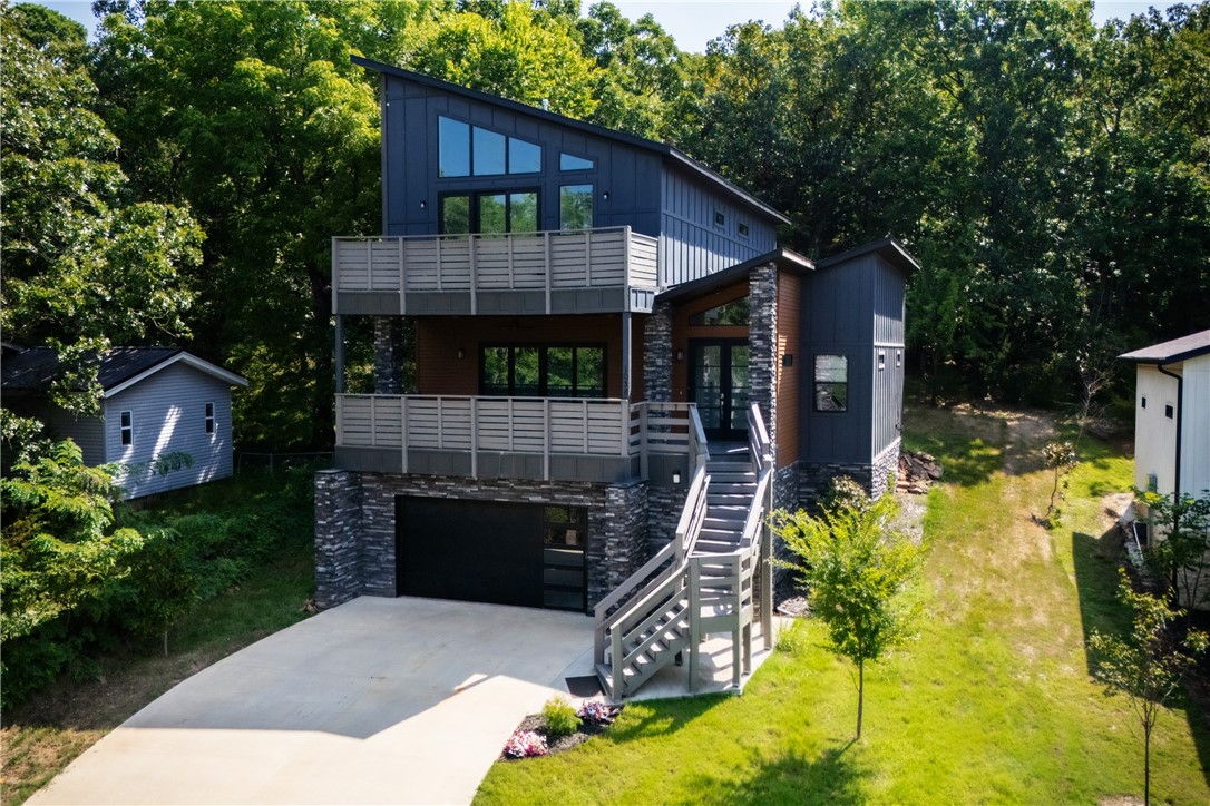 Stunning Hilltop Retreat with Breathtaking Views of Old Main. Perched at the top of a quiet hill near Root Elementary School, this exceptional Fayetteville residence offers panoramic views of Old Main and unforgettable sunsets from two expansive west-facing patios. Backing up to a serene wooded area filled with deer and native wildlife, this home provides unmatched privacy and a true connection to nature, all while being minutes from the heart of town. Thoughtfully designed with comfort and luxury in mind, the home features two spacious primary suites, each with a private bathroom boasting elegant tilework and freestanding soaking tubs. Modern hardwood floors, plentiful windows, and large sliding glass doors flood the home with natural light, while contemporary fixtures and premium KitchenAid stainless appliances add style and convenience.The fully finished walkout basement includes a bonus room and a media space.