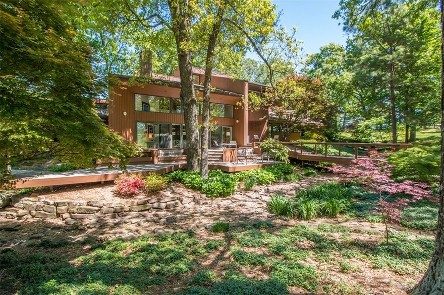 This parklike landscaped setting on 11.75 acres offers privacy w/accessibility in this one-of-a-kind 5,190 sf light-filled contemporary Redwood home. Minutes from I-49, this custom one owner AIA architect designed home boasts of natural elements of stone & woodwork.  Enjoy 3 bedrooms, 3.5 bathrooms, floor to ceiling windows, multiple living spaces, spa, slate flooring, office & abundant storage. Outside enjoy multiple redwood decks, waterfall, inground pool, 35x90 workshop (half is heated w/cable) w/deck & pond.