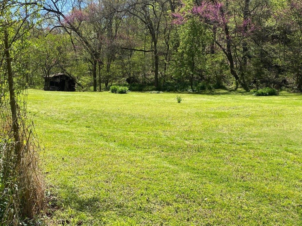 Secluded 40(+/-) acres, 2 live creeks run year round, spring on hillside piped to the house has provided water for many years. Flagstone 2 story house was built around 1932 and has been in same family until present day, would be considered uninhabitable as it has no modern facilities and has termite damage. Barn and pole barn in poor condition. Setting is beautiful as it is a level valley with steep hills on every side except the level entry over a bridge.