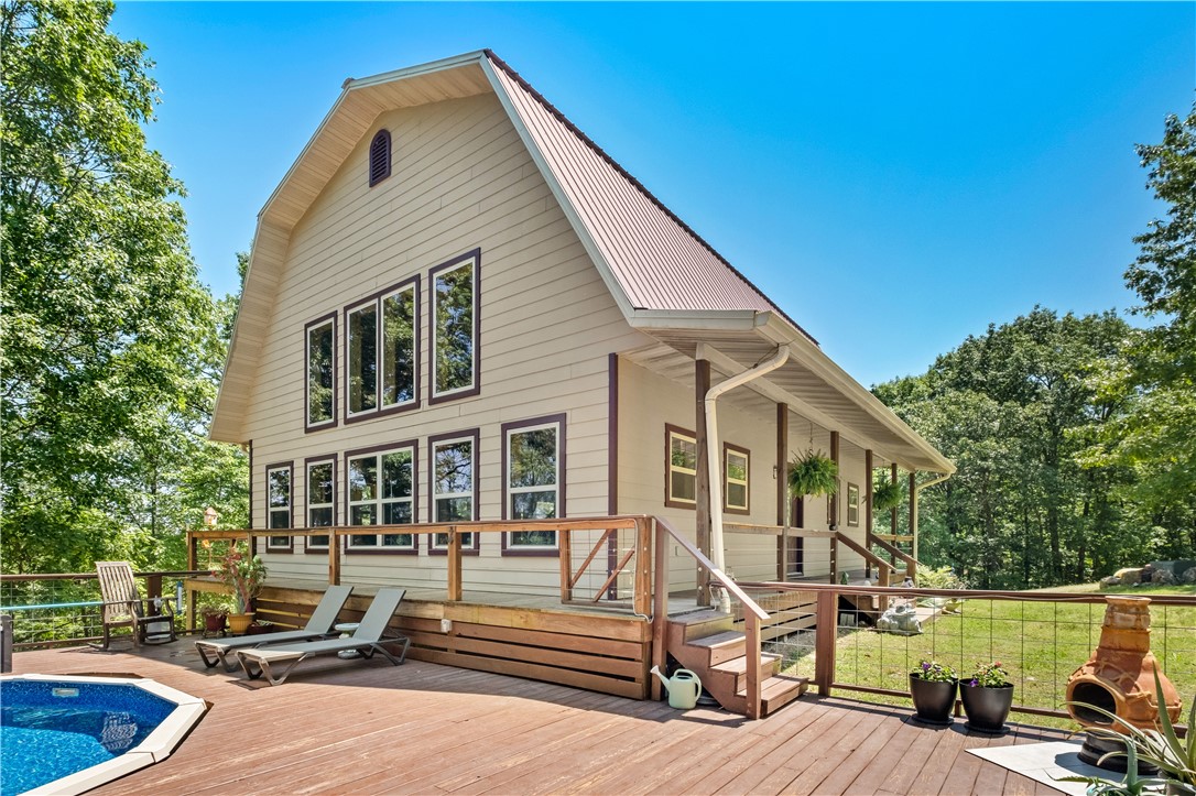 Start living your best life in this beautiful mountain-top home on 4.3 acres with a seasonal view of Lake Lucerne. The stunning living area has vaulted knotty pine tongue-and-groove ceilings and a wall of windows overlooking the pool and deck. The open floor plan has a dining area and a gourmet kitchen with an island and glass tile accent walls. Custom soft-close drawers and cabinets provide ample storage and there's a pantry with a frosted glass door. The main level bedroom is spacious and adjoins a marble tiled bath/shower and laundry area. Upstairs is a large loft bedroom with a vaulted knotty pine ceiling, a full bath and a walk-in closet. Outdoor entertaining is a breeze with wrap-around decks on three sides of the home. The back lower level has a carport for two vehicles. A 12ā x 24ā she shed and a 12ā x 14ā storage/workshop provide the perfect spots to enjoy your hobbies. Low maintenance cement plank siding and a metal roof. Great second home/nightly rental, only 3.5 miles to downtown Eureka Springs.